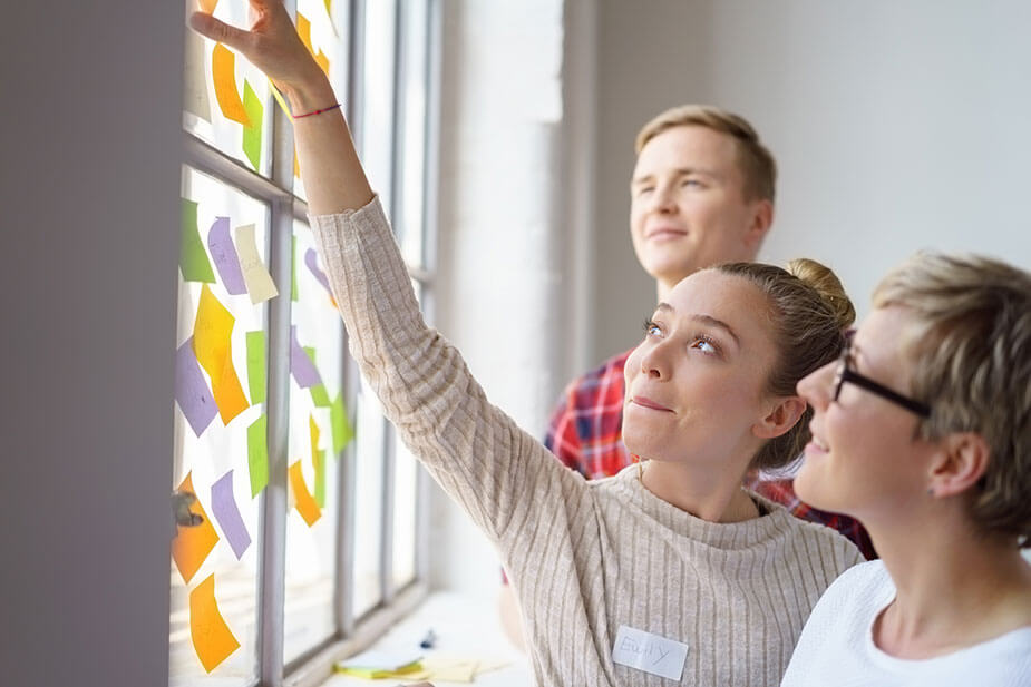 Frau platziert Post-Its an Fenster