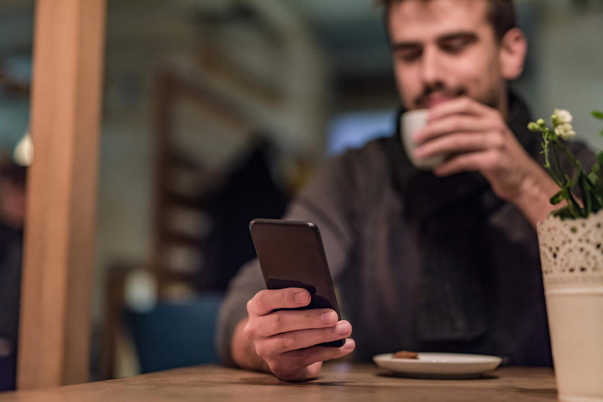 Mann sitzt im Café mit Handy