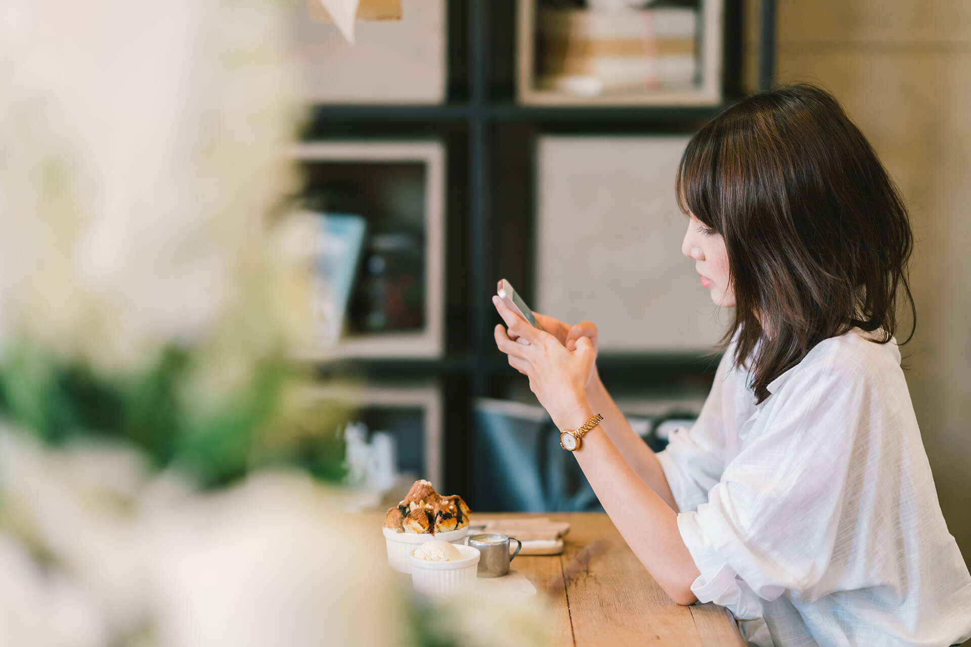 Frau sitzt im Café mit Handy