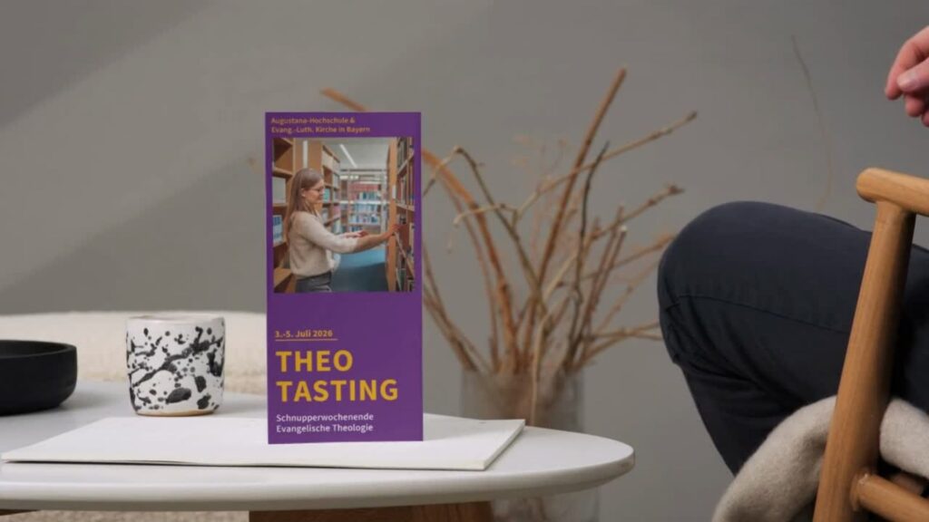 Auf einem weißen Tisch steht eine violette „Theo Tasting“-Broschüre neben einer schwarzen Schale; daneben sitzt eine Person, und im Hintergrund sind getrocknete Zweige zu sehen.